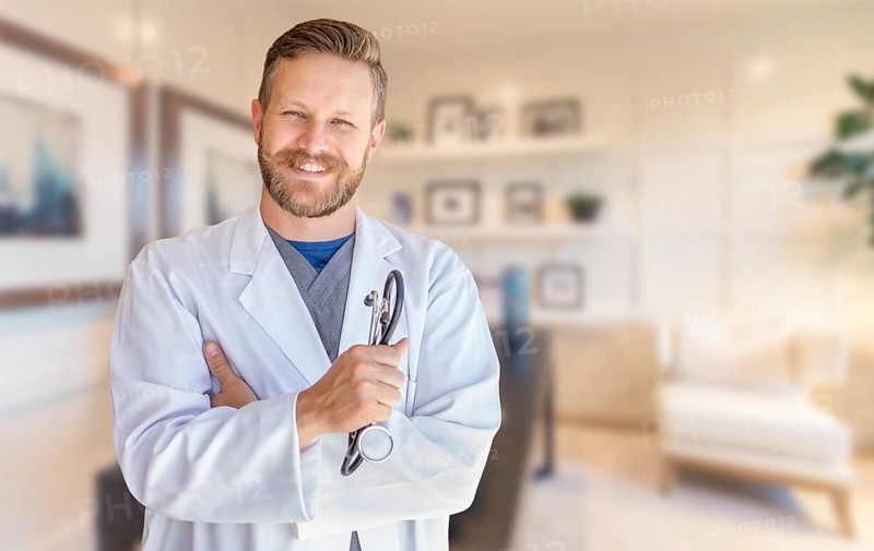 Handsome young adult male doctor with beard inside office