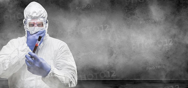 Man wearing hazmat suit and goggles holding test tube of blood in smokey room banner with copy space