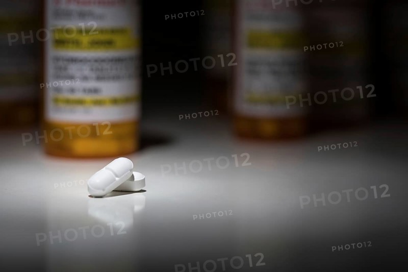Hydrocodone pills and prescription bottles under spot light