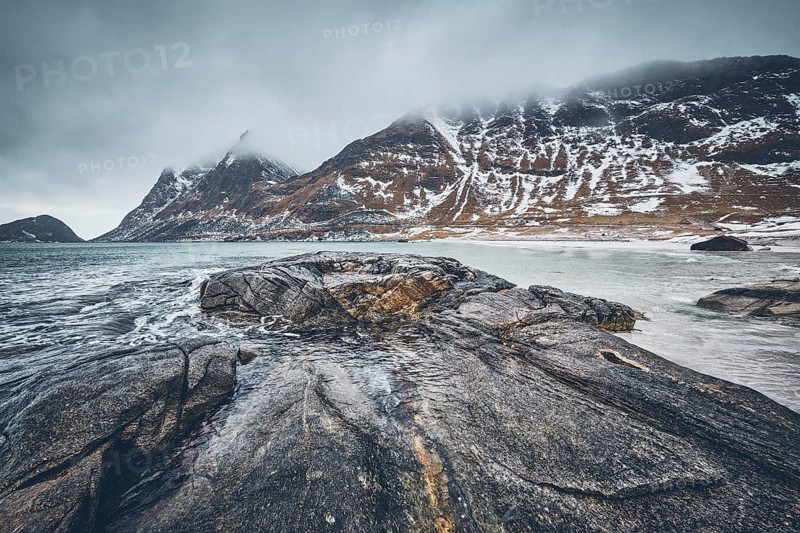 Rocky coast of fjord of Norwegian sea in winter with snow. Haukland beach