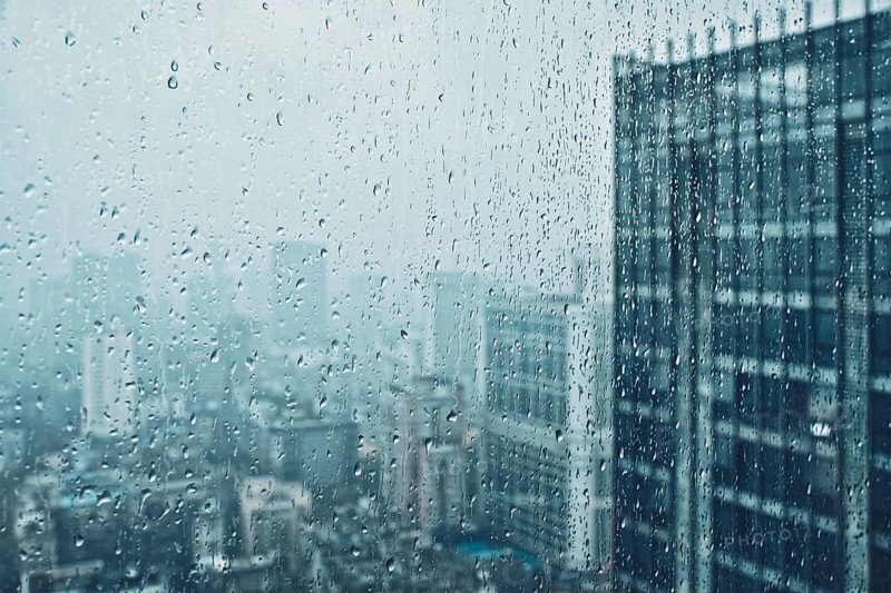 Rain water drops droplets on window glass texture with skyscrapers in background
