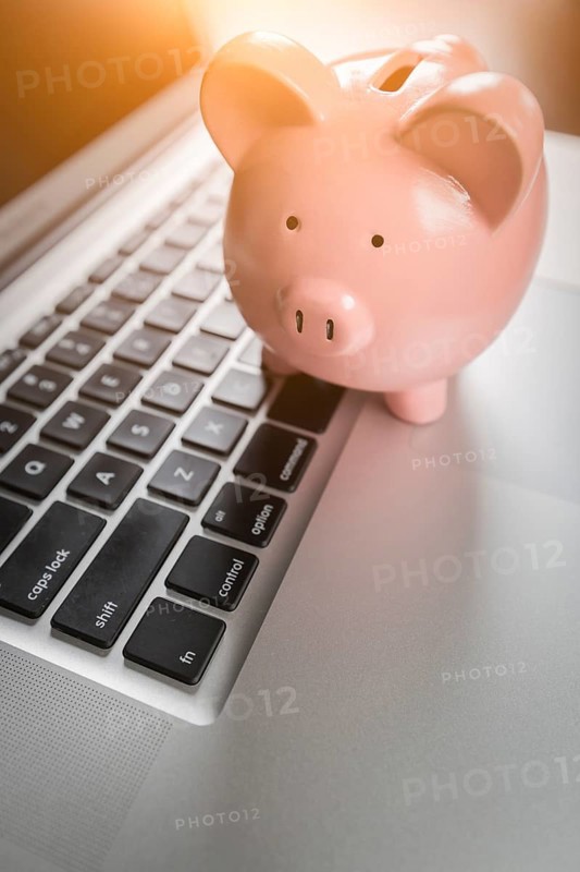 Piggy bank resting on laptop computer keyboard