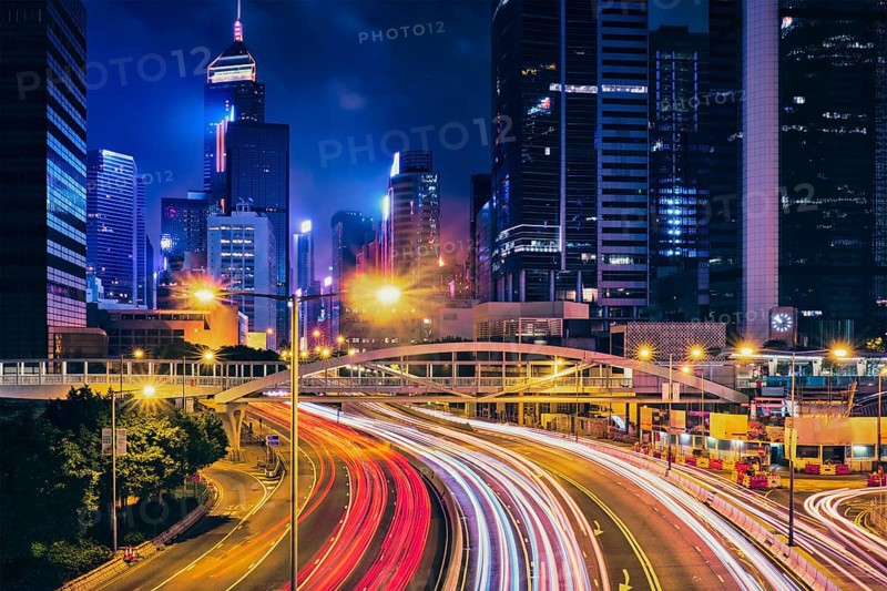 Street traffic in Hong Kong at night. Office skyscraper buildings and busy traffic on highway road with blurred cars light trails. Hong Kong