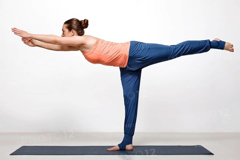 Beautiful sporty fit woman practices yoga asana Virabhadrasana 3