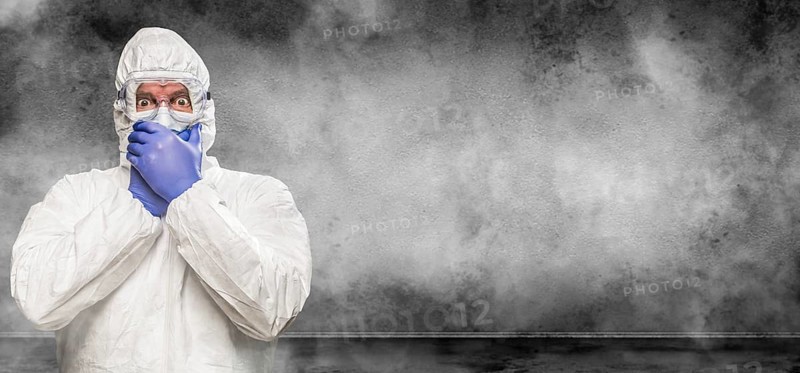 Man wearing hazmat suit and goggles in smokey room banner with copy space