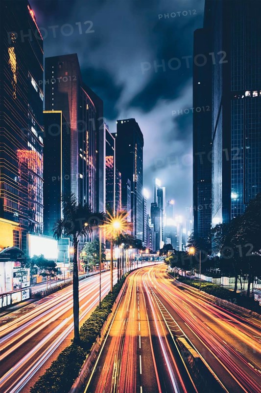 Street traffic in Hong Kong at night. Office skyscraper buildings and busy traffic on highway road with blurred cars light trails. Hong Kong
