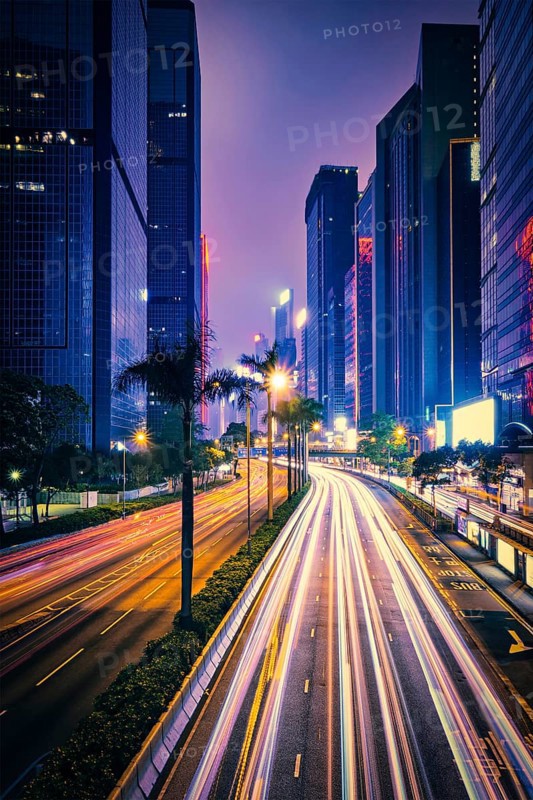 Street traffic in Hong Kong at night. Office skyscraper buildings and busy traffic on highway road with blurred cars light trails. Hong Kong
