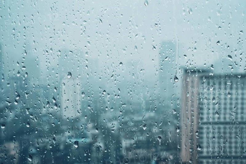 Rain water drops droplets on window glass texture with skyscrapers in background