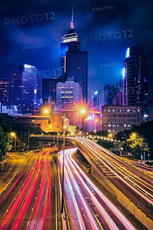Street traffic in Hong Kong at night. Office skyscraper buildings and busy traffic on highway road with blurred cars light trails. Hong Kong