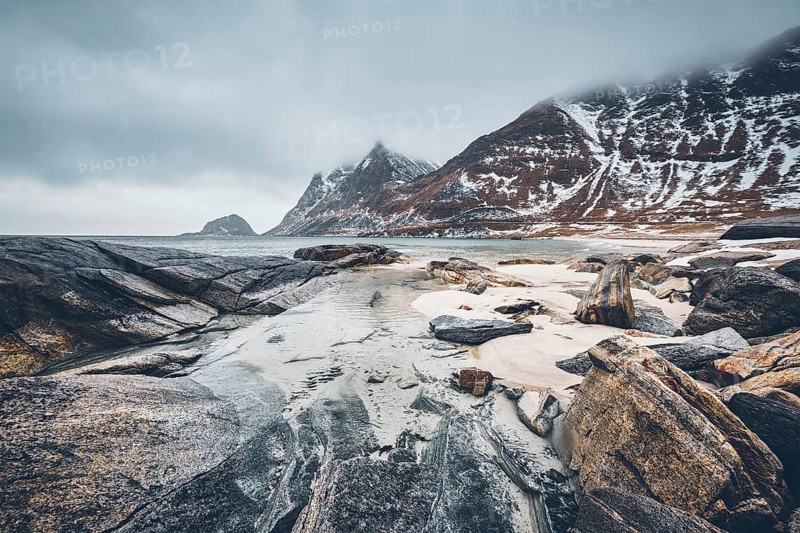 Rocky coast of fjord of Norwegian sea in winter with snow. Haukland beach
