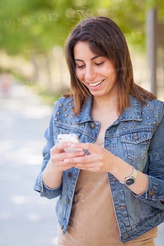 Beautiful young ethnic woman using her smartphone outside