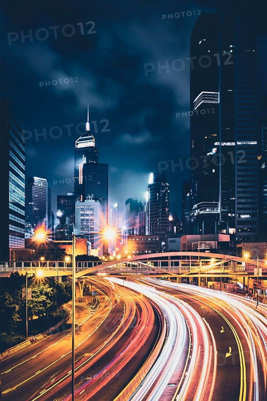 Street traffic in Hong Kong at night. Office skyscraper buildings and busy traffic on highway road with blurred cars light trails. Hong Kong