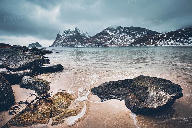 Rocky coast of fjord of Norwegian sea in winter with snow. Haukland beach