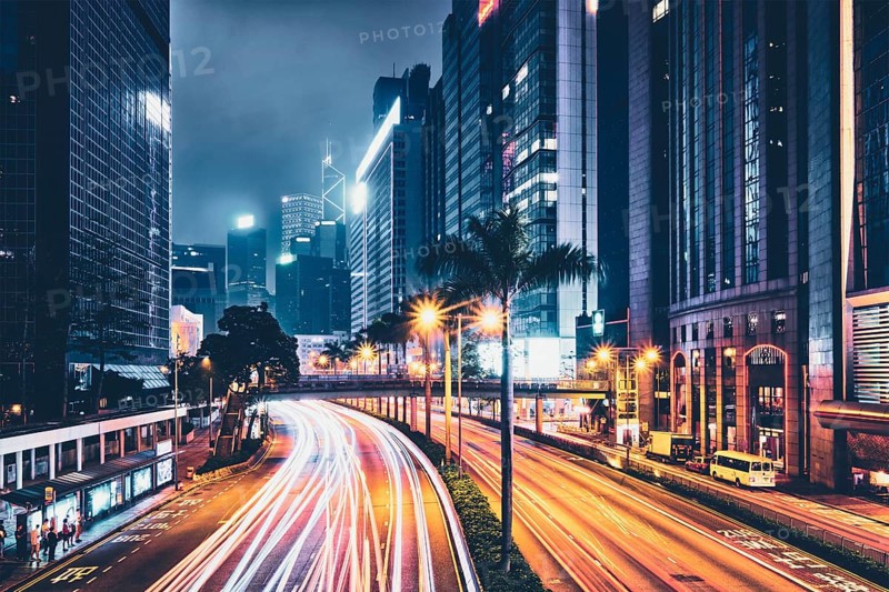 Street traffic in Hong Kong at night. Office skyscraper buildings and busy traffic on highway road with blurred cars light trails. Hong Kong