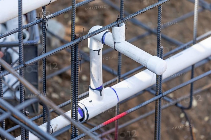 Newly installed PVC plumbing pipes and steel rebar configuration at construction site