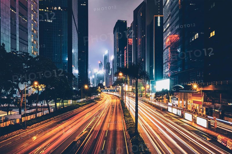 Street traffic in Hong Kong at night. Office skyscraper buildings and busy traffic on highway road with blurred cars light trails. Hong Kong