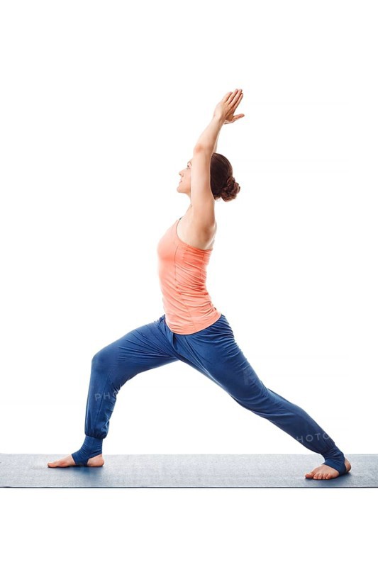 Beautiful sporty fit yogini woman practices yoga asana Virabhadrasana 1