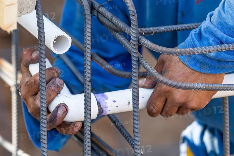 Plumber installing PVC pipe at construction site