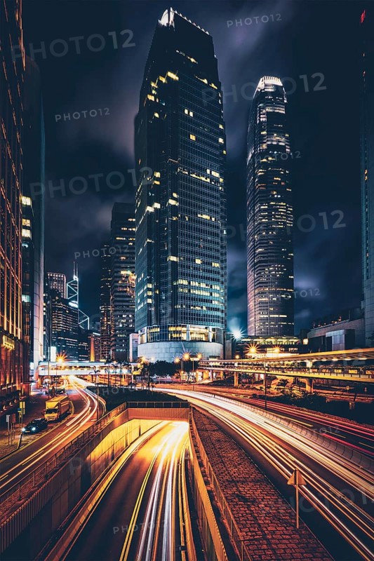 Street traffic in Hong Kong at night. Office skyscraper buildings and busy traffic on highway road with blurred cars light trails. Hong Kong