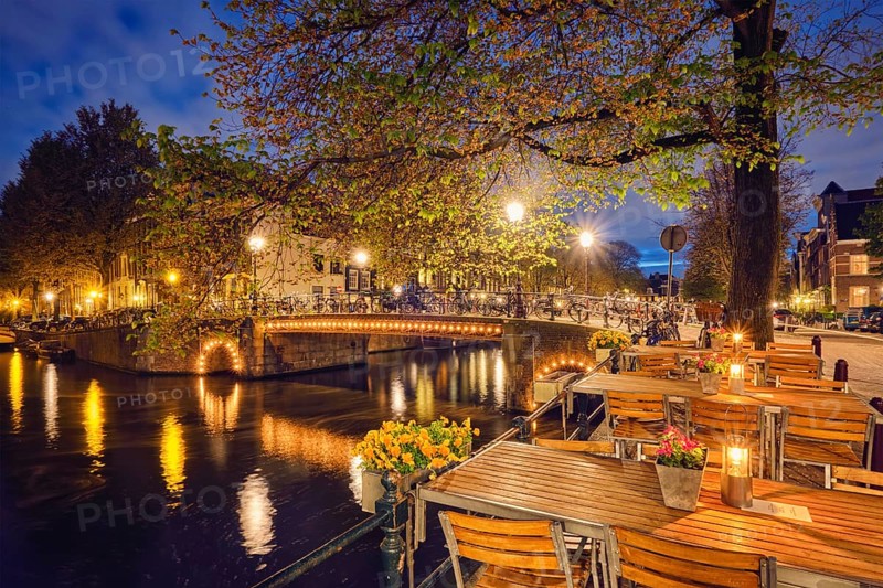 Night view of Amterdam cityscape with cafe tables