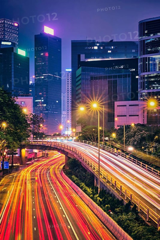 Street traffic in Hong Kong at night. Office skyscraper buildings and busy traffic on highway road with blurred cars light trails. Hong Kong