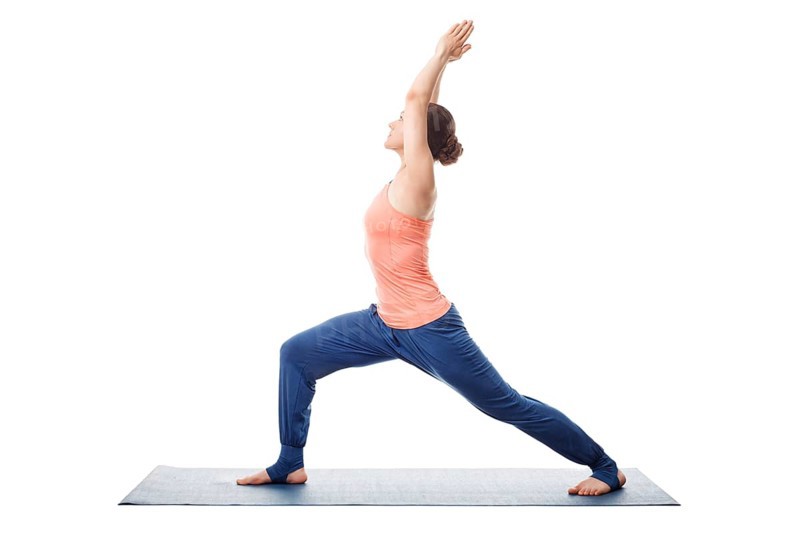 Beautiful sporty fit yogini woman practices yoga asana Virabhadrasana 1