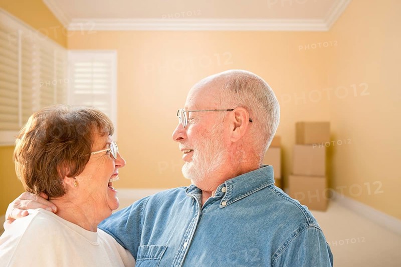 Happy senior couple in room with moving boxes on the floor