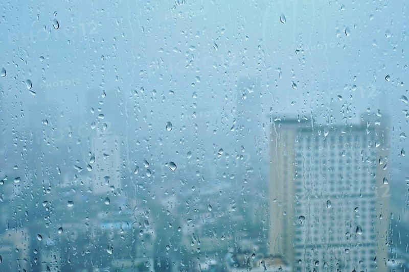 Rain water drops droplets on window glass texture with skyscrapers in background