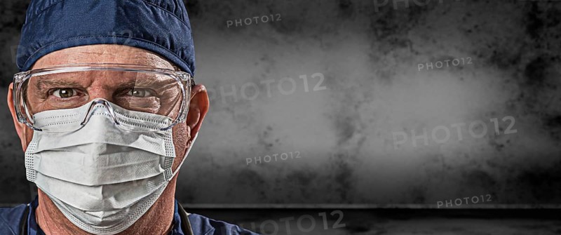 Male doctor or nurse wearing goggles and face mask against grungy dark background banner