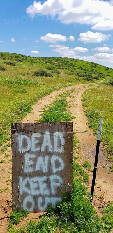 Dead end keep out sign on wire fence at dirt road