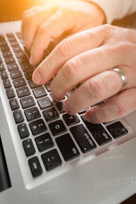 Male hands typing on laptop computer keyboard