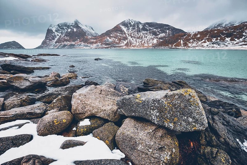 Rocky coast of fjord of Norwegian sea in winter with snow. Haukland beach