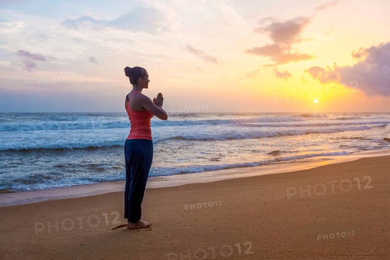 Woman doing Ashtanga Vinyasa Yoga asana Tadasana Samasthiti yoga posture on beach