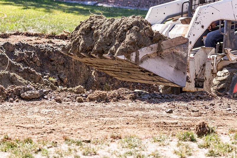Small bulldozer digging in yard for pool installation