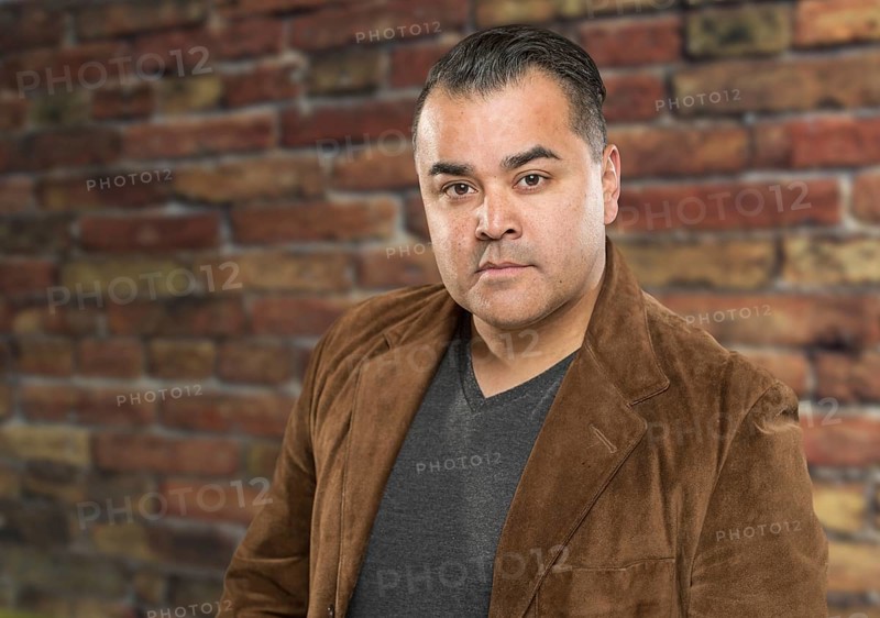 Handsome young hispanic male headshot portrait against brick wall