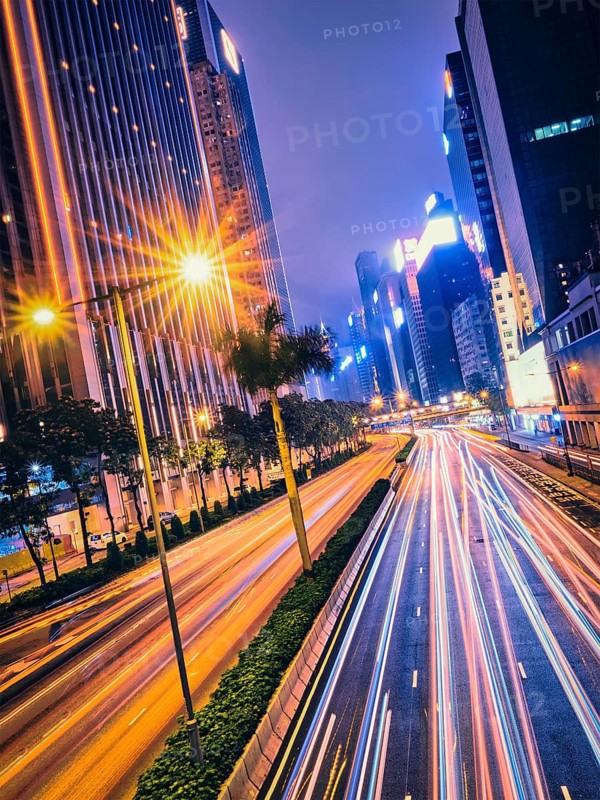 Street traffic in Hong Kong at night. Office skyscraper buildings and busy traffic on highway road with blurred cars light trails. Hong Kong