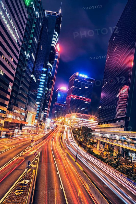 Street traffic in Hong Kong at night. Office skyscraper buildings and busy traffic on highway road with blurred cars light trails. Hong Kong