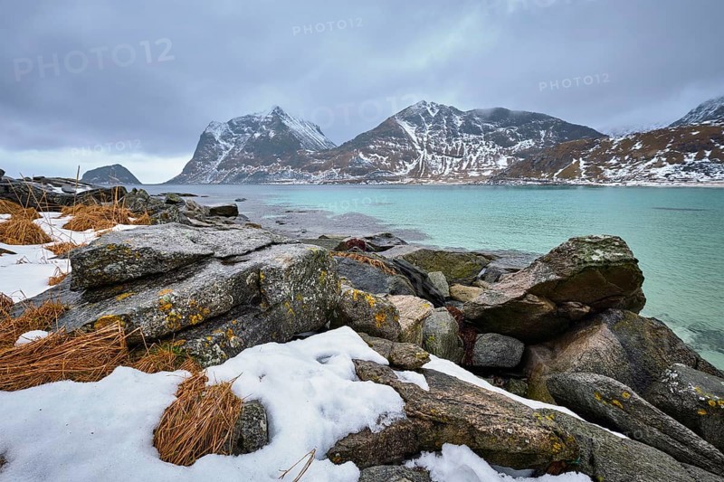 Rocky coast of fjord of Norwegian sea in winter with snow. Haukland beach