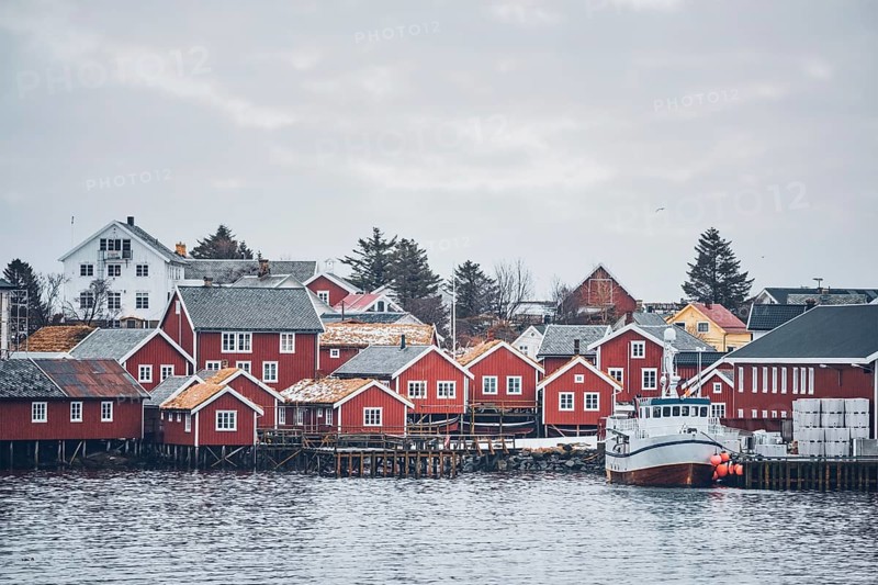 Reine fishing village on Lofoten islands with red rorbu houses in winter with snow with fishing boats. Norway