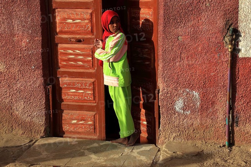 Young girl with headscarf standing in front of the door in a Nubian village in Upper Egypt