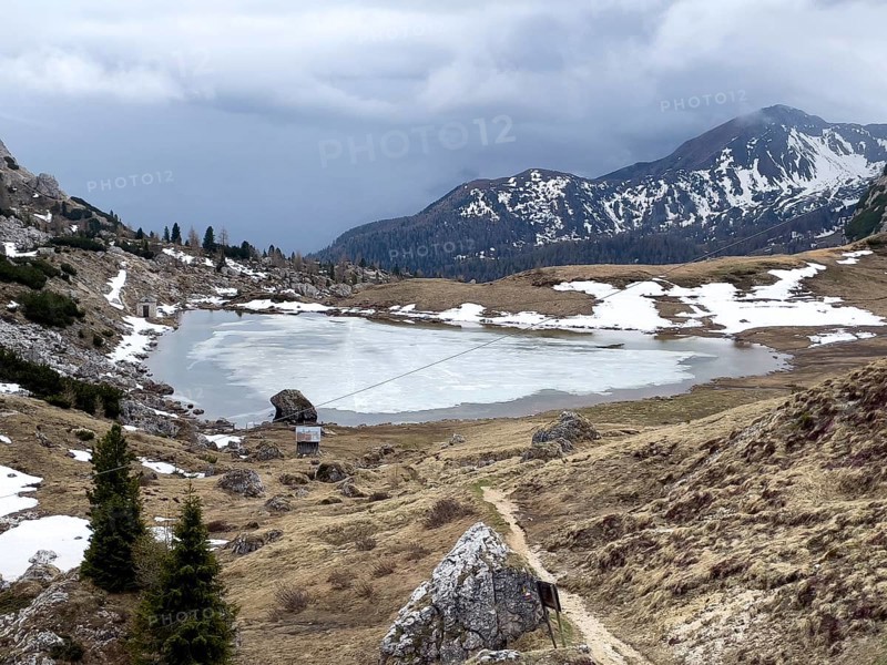 Mountain lake Lago di Valparola with thawing ice surface
