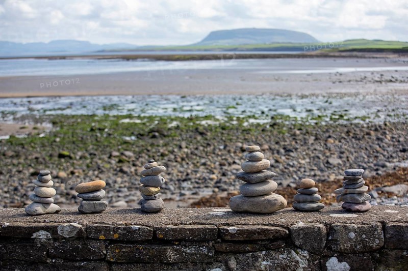 Columns of pebbles on a stone wall in Ireland with a view of Knocknarea in the background. Sligo