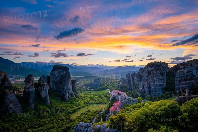 Sunset sky and monastery of Rousanou and Monastery of St. Nicholas Anapavsa in famous greek tourist destination Meteora in Greece with sun rays and lens flare