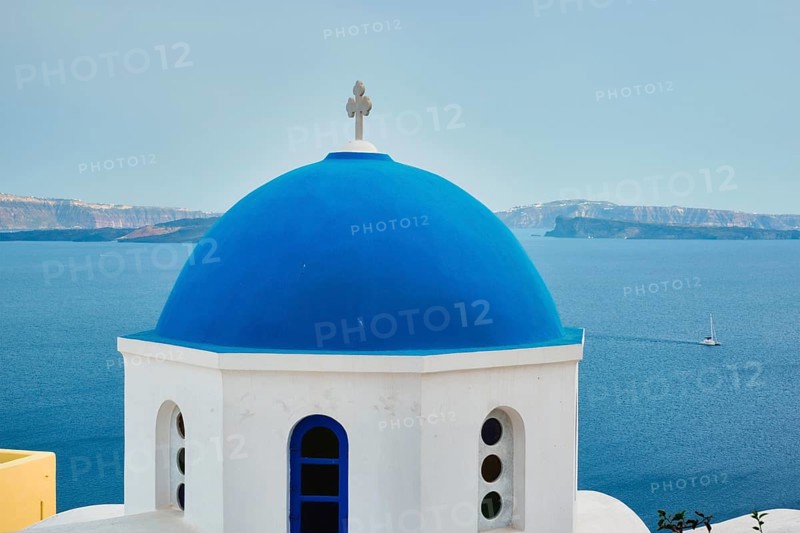 Famous view from viewpoint of Santorini Oia village with blue dome of whitewashed greek orthodox Christian church of traditional greek architecture