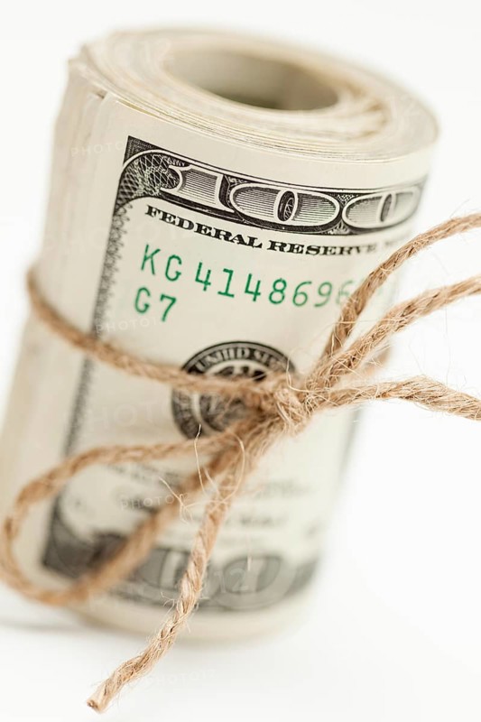 Roll of one hundred dollar bills tied in burlap string on white