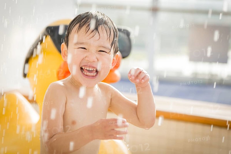 mixed-race boy having fun at the water park with large rubber duck in the background