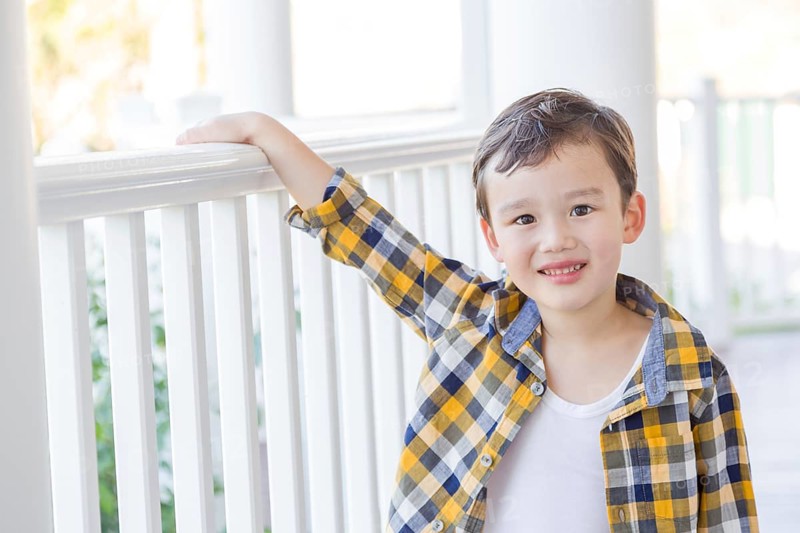Young mixed-race chinese and caucasian boy on his front porch