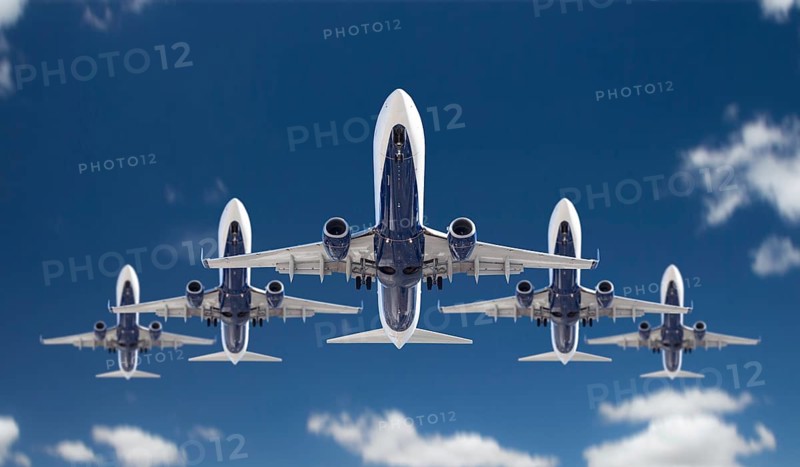 Bottom view of five passenger airplanes flying in formation in the blue sky