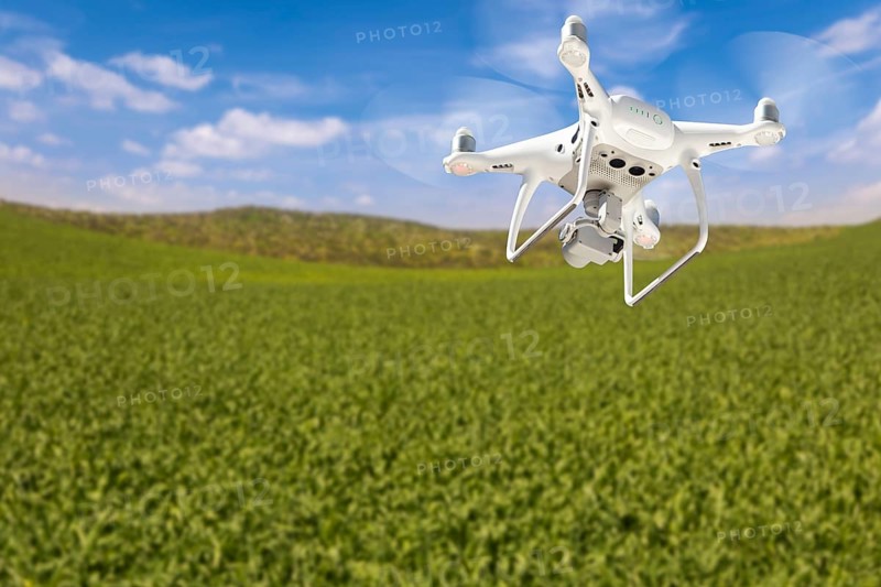 Drone unmanned aircraft flying and gathering data over country farmland