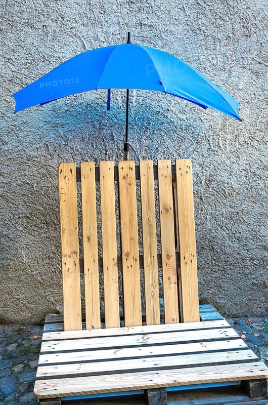 Seat made of old wooden pallets with blue umbrella